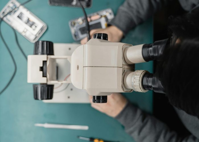 Close-up of a technician using a microscope for phone repair, highlighting precision work.